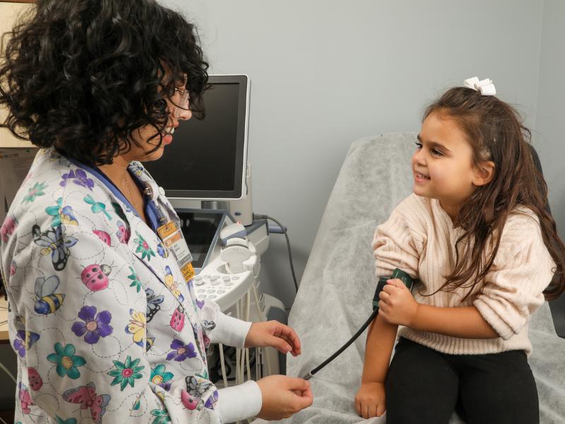a clinical nurse researcher performs a blood pressure check of a young girl